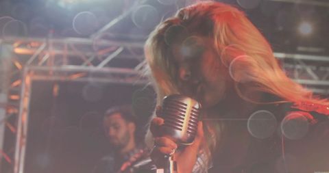 Female Vocalist Holding Retro Microphone on Stage During Concert