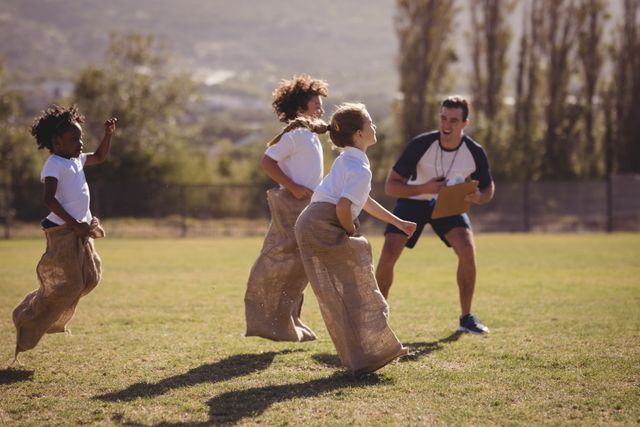 Coach cheering schoolgirls during a sack race in a park on a sunny day. Ideal for illustrating outdoor activities, school events, physical education, teamwork, and children's sports. Perfect for educational materials, fitness programs, and recreational event promotions.