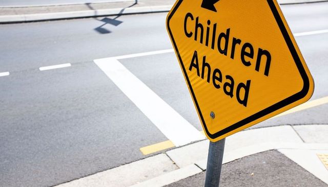 Children ahead sign at crosswalk in urban intersection highlighting pedestrian safety