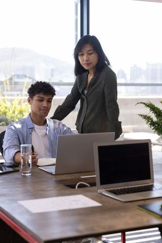 Diverse Coworkers Collaborating in Modern Office with Laptops