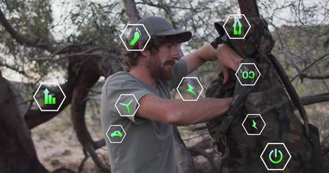 Adventurous male hiker fitting camouflage backpack with technology icons