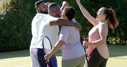 Diverse Friends Celebrating Victory on Tennis Court with High Fives