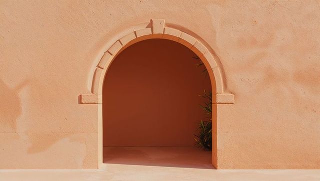 Sunlit terracotta archway casting diagonal shadow over minimalist courtyard alcove