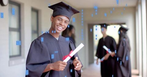 Smiling graduate holding diploma in corridor celebrating academic achievement and success