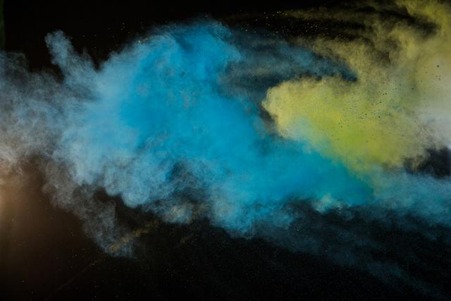 Dynamic explosion of blue and yellow color powder against a black background. Energetic and dramatic image perfect for artistic projects, advertising, and creative presentations. Ideal for use in design and marketing materials needing bold and vibrant color contrasts.