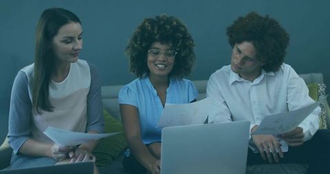 Diverse Team Collaborating with Laptops and Documents in Modern Office