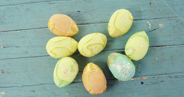 Colorful decorative Easter eggs arranged on a distressed blue wooden surface. Perfect for Easter celebrations, holiday craft projects, spring décor inspiration, party invitations, and greeting card designs.