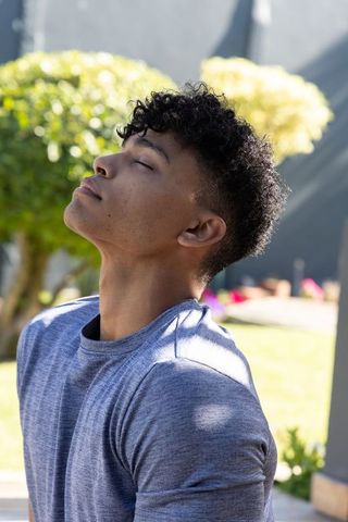 Young african american man practicing mindful breathing outdoors in sunny garden backyard