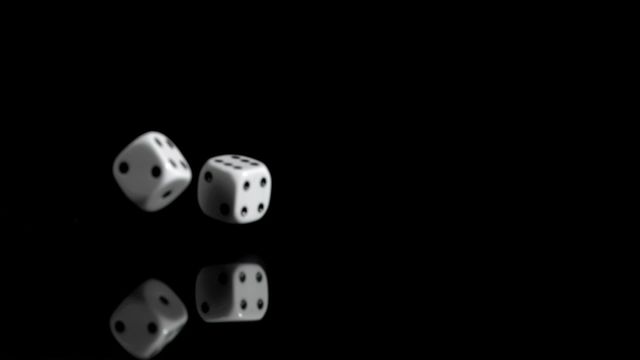 White dice bouncing and reflecting against a black background create a dramatic visual. Ideal for themes related to gambling, games of chance, luck, or recreation. Great for illustrations or advertising for gaming apps, casinos, or board games.