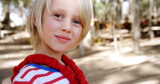 A young Caucasian child is smiling outdoors, with copy space. Captured in a natural setting, the child's cheerful expression conveys a sense of innocence and joy.