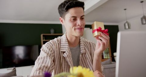 Joyful Man Holding Gift on a Video Call at Home