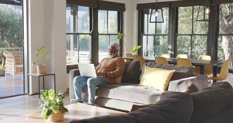 Senior man using laptop in cozy bright living room