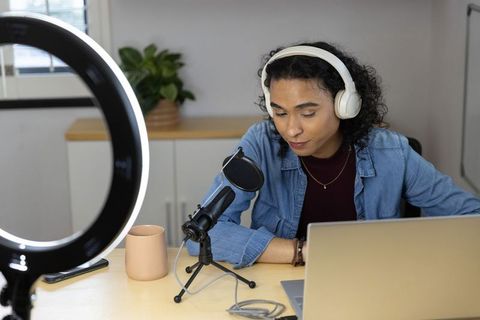 Nonbinary creator recording podcast home workstation with ring light, microphone, laptop