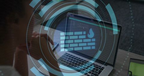 Laptop Showing Firewall Icon with Futuristic HUD Overlay While Woman Reviews Code on Desk
