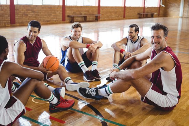 Smiling basketball players interacting while relaxing in the court