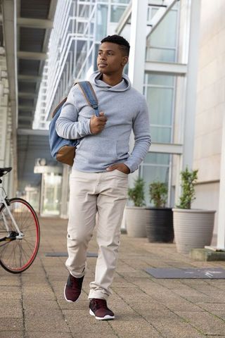 Walking african american man carrying backpack on modern urban walkway casual commuter