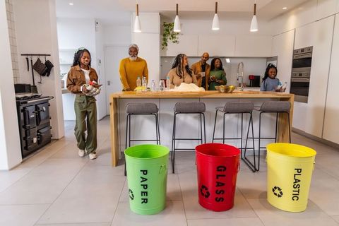 Multigenerational african american family gathering in kitchen sorting recycling bins
