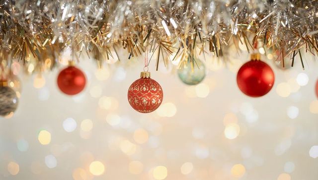 Shimmering Red Patterned Bauble Hanging from Gold Tinsel with Warm Bokeh Lights