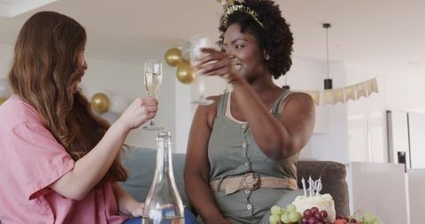 Cheerful Same-Sex Couple Celebrating Birthday at Home with Champagne