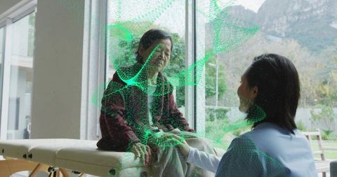 Holding hands caregiver kneeling beside senior during augmented reality therapy at home