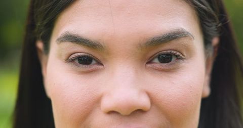 Woman in garden gazing, highlighting natural beauty with radiant skin and eyes