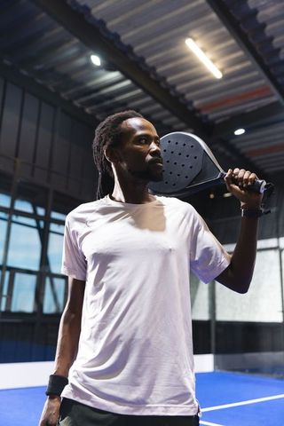 African american athlete holding padel racket on blue court