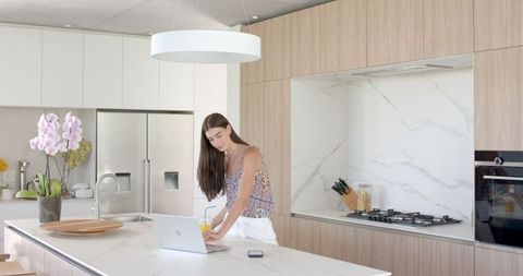 Teen Girl Engaging with Laptop in Modern Kitchen Interior