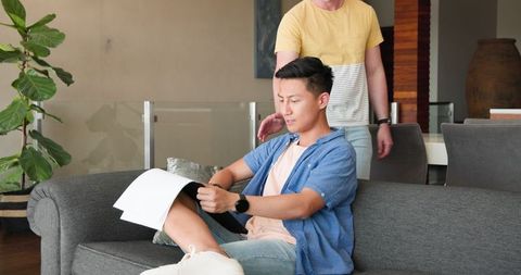 Asian Couple Relaxing in Living Room, Sharing Joyful Moments Together