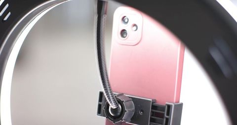 Metallic pink smartphone mounted in led ring light clamp for content creators and live streaming