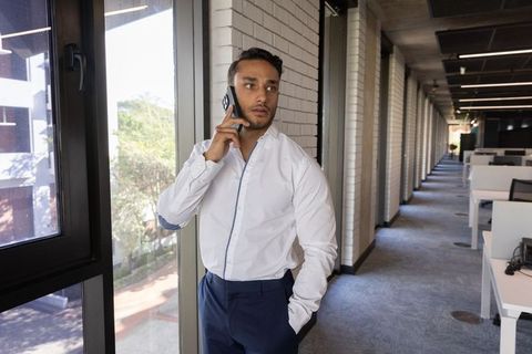 Professional Businessman Talking on Phone in Modern Office Corridor