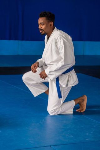Man practicing martial arts in white gi and blue belt