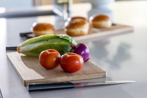 Sunlit tomatoes on cutting board with romaine and onion for fresh sandwich preparation