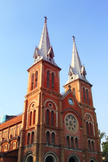 Image depicting two Gothic Revival-style church steeples against a clear blue sky. These tall, pointed, symmetrical constructions symbolize religious and historical significance. Ideal for illustrating travel brochures, magazines, architecture blogs, or articles on heritage preservation. Versatile use for religious and cultural studies, promoting tourism or highlighting beautiful architectural designs.