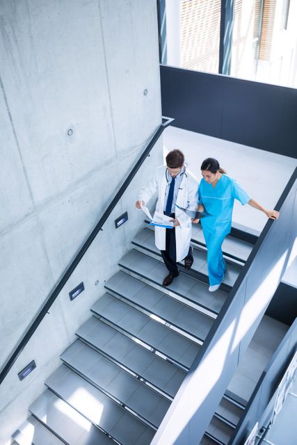 Doctor and nurse discussing over a report while climbing down stairs in hospital