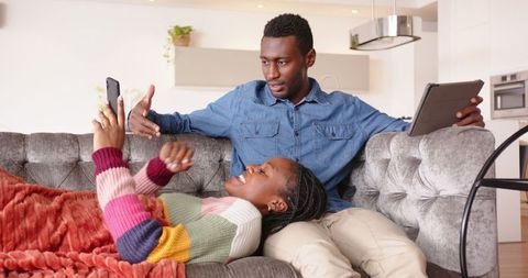 African American Couple Relaxing Comfortably with Tech Devices at Home