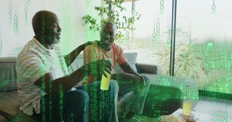 Senior man sharing drink with adult son on sofa, companionship with green digital overlay