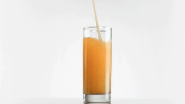 Tall transparent glass being filled with fresh mango juice on white background. Great for use in advertising healthy drinks, breakfast menus, or promoting tropical products. Perfect for blogs on nutrition or lifestyle-focused articles needing lively visuals.