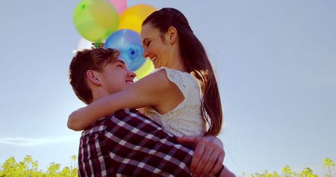 Young Couple Embracing with Balloons Against Blue Sky Backdrop - Download Free Stock Images Pikwizard.com