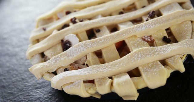 A close-up view of an uncooked lattice pie crust sprinkled with sugar, showcasing the intricate weaving of the dough. The image captures the preparation stage of a delicious dessert, emphasizing the attention to detail in pastry making.