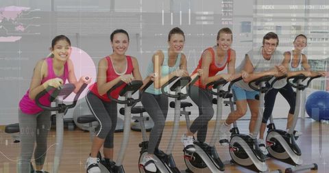 Group spin class with happy attendees on exercise bikes
