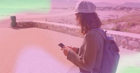 Traveler with Backpack Checking Smartphone by the Sea Promenade