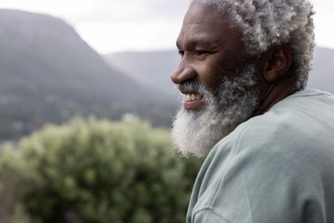 Smiling african american senior enjoying mountain overlook, white beard, outdoor lifestyle