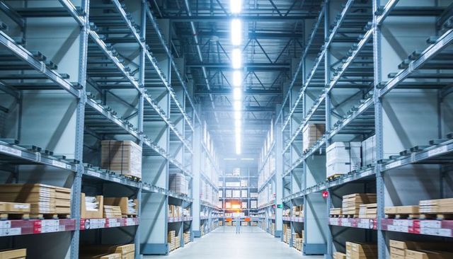 Central aisle stretching through high-ceiling warehouse with metal racking and pallet boxes