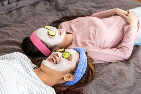 Mother and daughter relaxing with skincare masks and cucumber slices