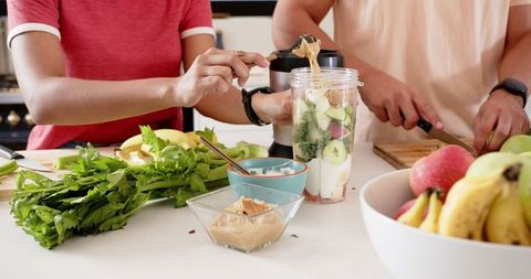 Couple Making Healthy Smoothie with Fruits and Vegetables in Kitchen