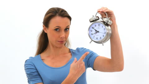 Surprised Woman Holding And Pointing At Vintage Alarm Clock