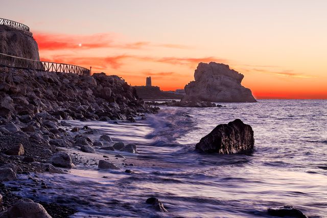 Rocky Coastline at Sunset with Calming Waves and Distant Cliffs - Download Free Stock Photos Pikwizard.com