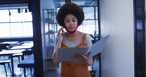 Businesswoman in Office Reviewing Paperwork During Telephone Call