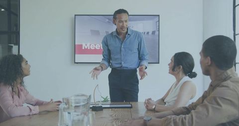 Business leader presenting to diverse team in modern boardroom during collaborative meeting