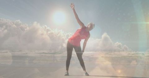 Senior Woman Exercising by Ocean Under Glowing Sun